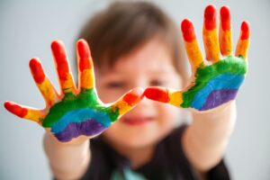 Niño mostrando las manos pintadas de colores para ilustrar un artículo sobre el trastorno del espectro autista (TEA).